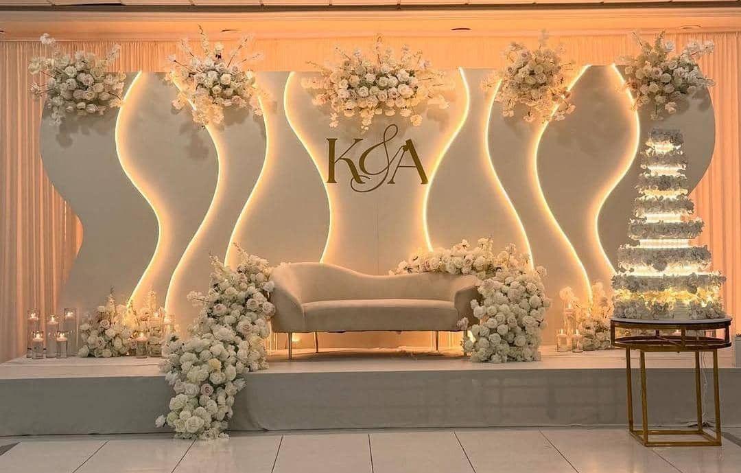 Sculptural ivory wedding stage with flowers and warm light